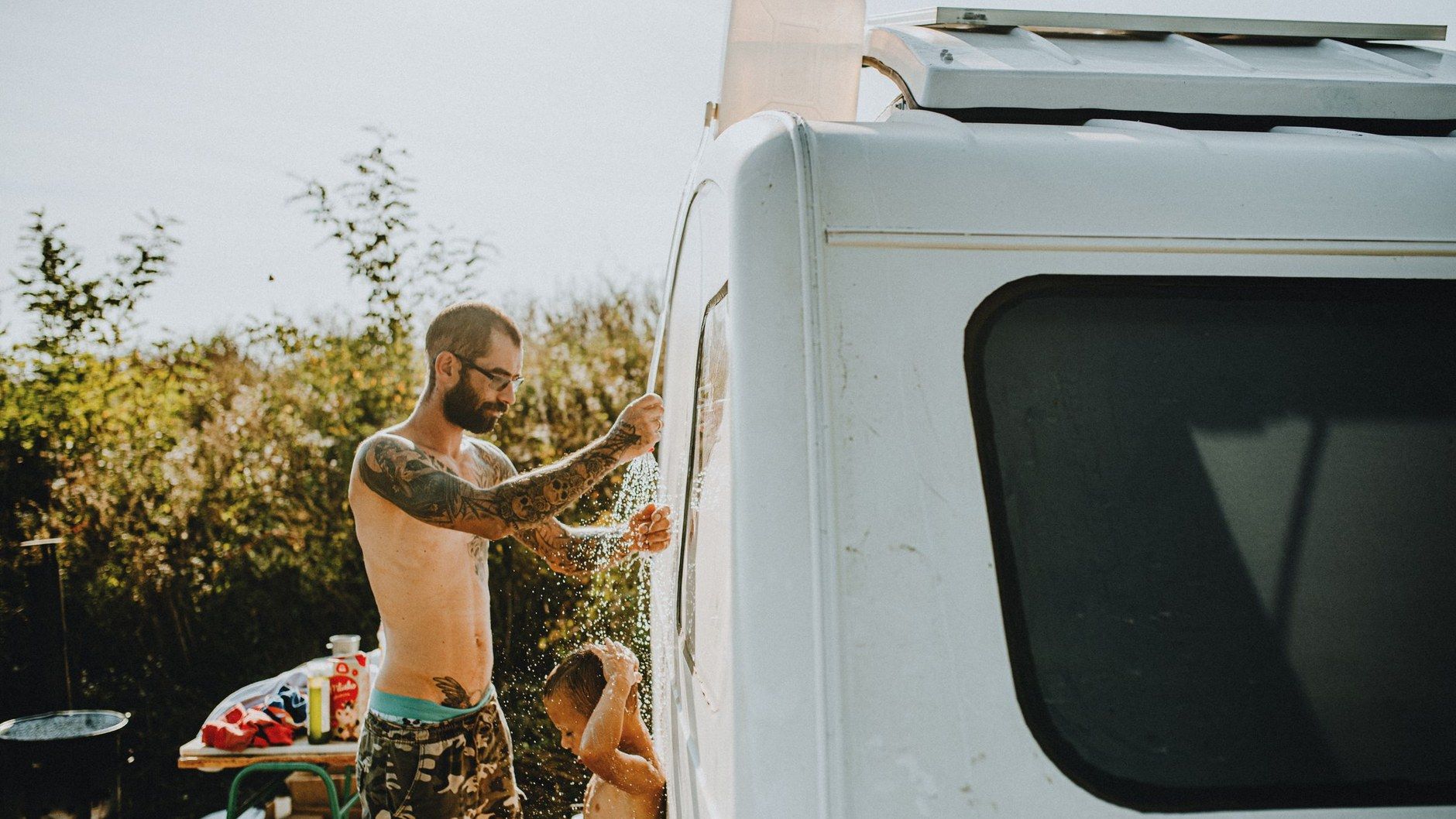 Outdoor-Dusche am Campervan: Person duscht im Sommer neben dem Wohnmobil auf dem Campingplatz
