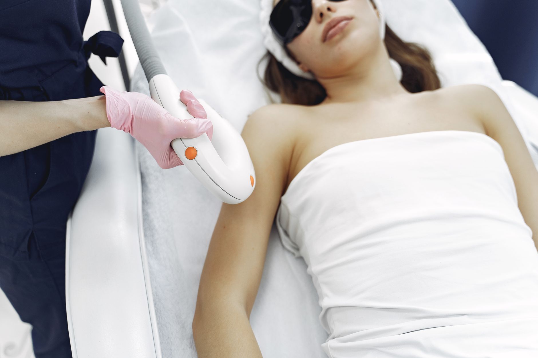 From above of unrecognizable cosmetologist in uniform and latex gloves using modern equipment for cosmetic services in contemporary salon
