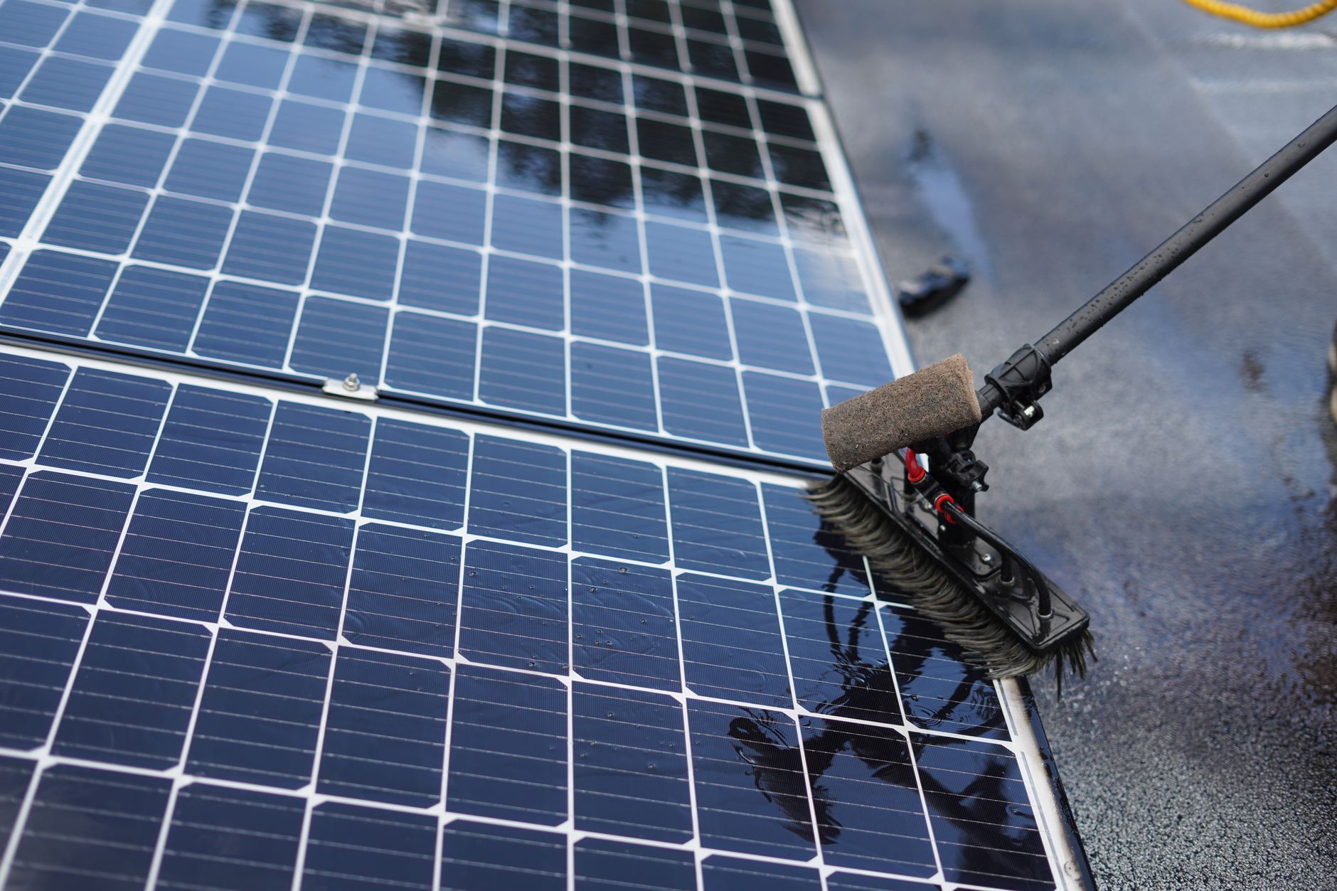 Reinigung eines Solarmoduls mit einer Waschbürste – Nahaufnahme der Panelfläche