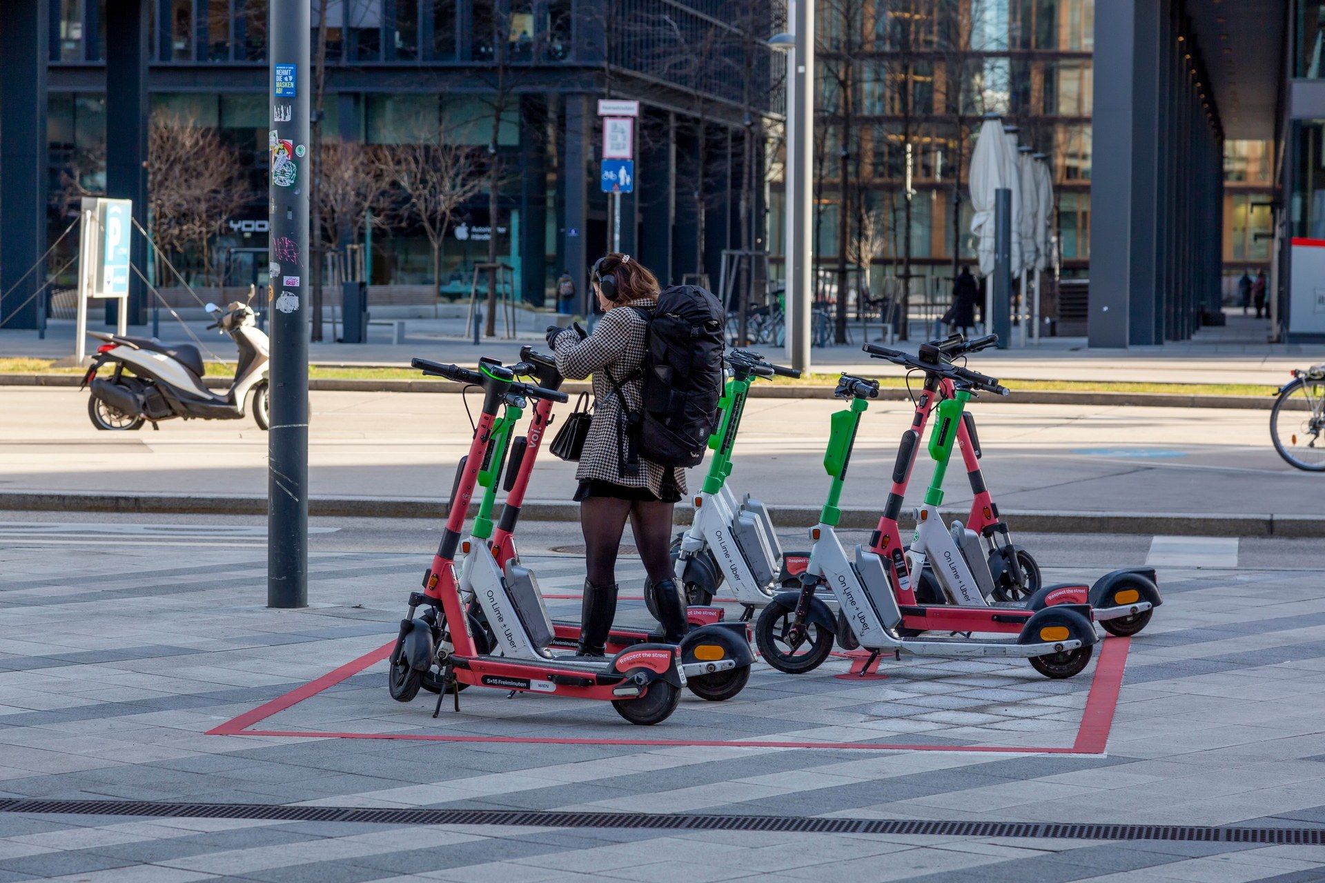 Person entleiht einen E-Scooter an einer markierten Abstellfläche im Stadtzentrum