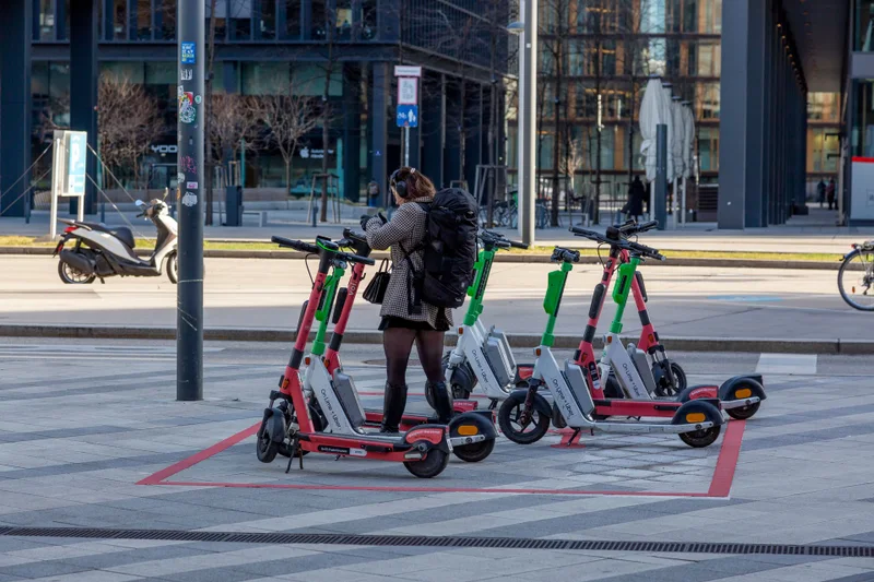 Person entleiht einen E-Scooter an einer markierten Abstellfläche im Stadtzentrum