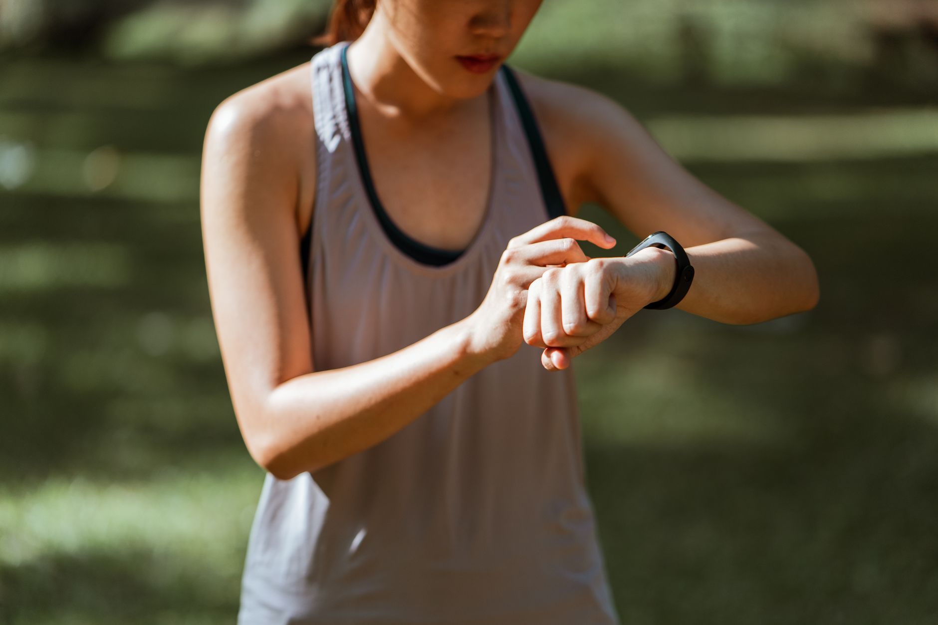 Frau prüft im Freien die Werte ihres Fitness-Trackers am Handgelenk